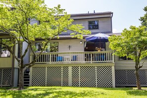 Une maison à deux étages avec une terrasse couverte et une cour arrière clôturée.