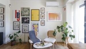 A living room with a sofa, chairs, a coffee table, and various framed artworks on the walls.