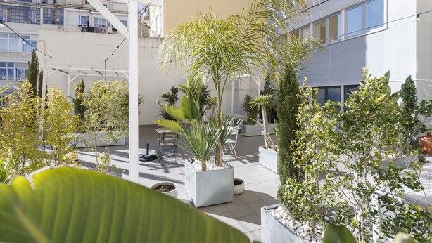 A courtyard with potted plants, outdoor seating, and a building with balconies.