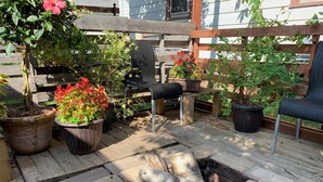 A wooden deck with potted plants, a fire pit, and outdoor furniture.