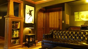 A cozy living room with a leather sofa, a bookshelf, a fireplace, and wooden doors.