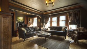 A spacious living room with a large leather sofa, a smaller sofa, a coffee table, and a fireplace.