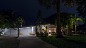 Ein modernes Haus mit einer überdachten Garage, einer Terrasse mit Gartenmöbeln und einem gepflegten Rasen.
