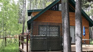 Eine Holzhütte mit einem Balkon und einem Geländer aus Metall, sowie einem blauen Sonnenschirm.
