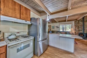 Une cuisine moderne équipée d’un réfrigérateur en acier inoxydable, d’une cuisinière à gaz et de meubles de rangement en bois.