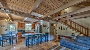 Ein geräumiger Wohnbereich mit Holzboden, einem Esstisch mit Stühlen, einer Couch und einer Treppe.
