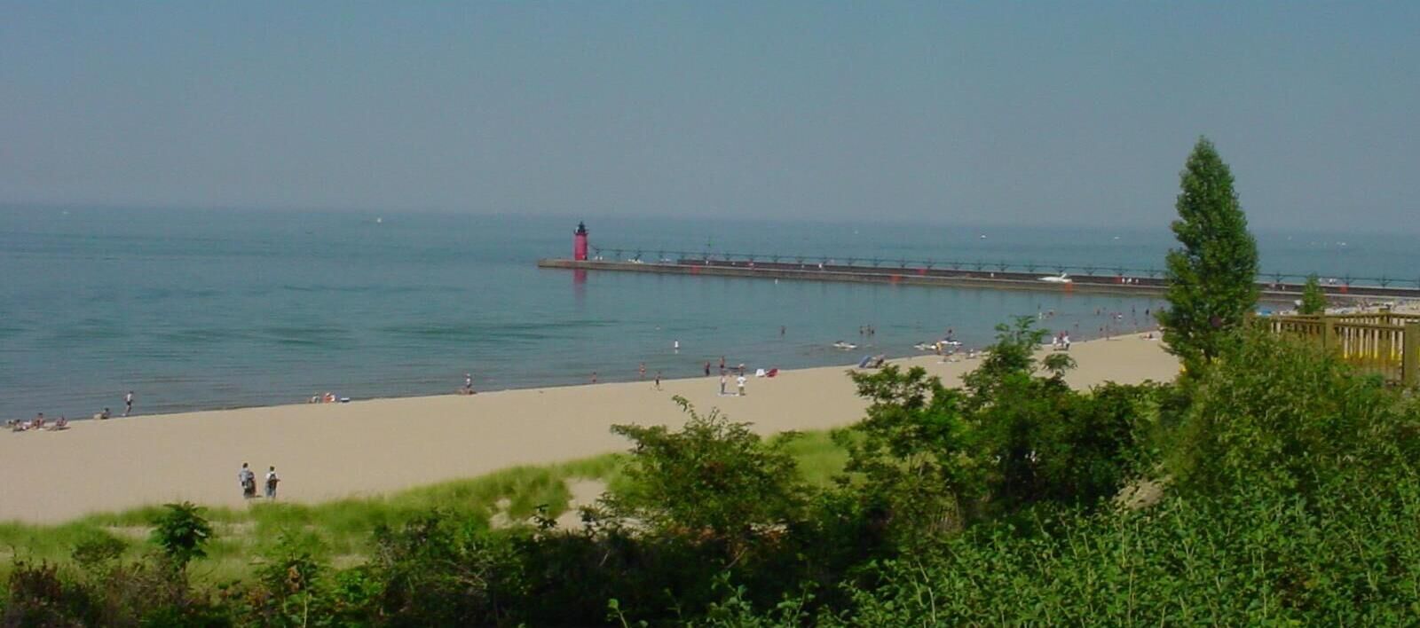 A beach with a pier and a lighthouse.