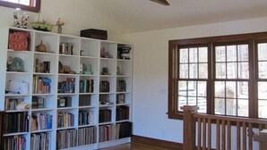 Una stanza con ventilatore a soffitto, una libreria, una finestra e una sedia.