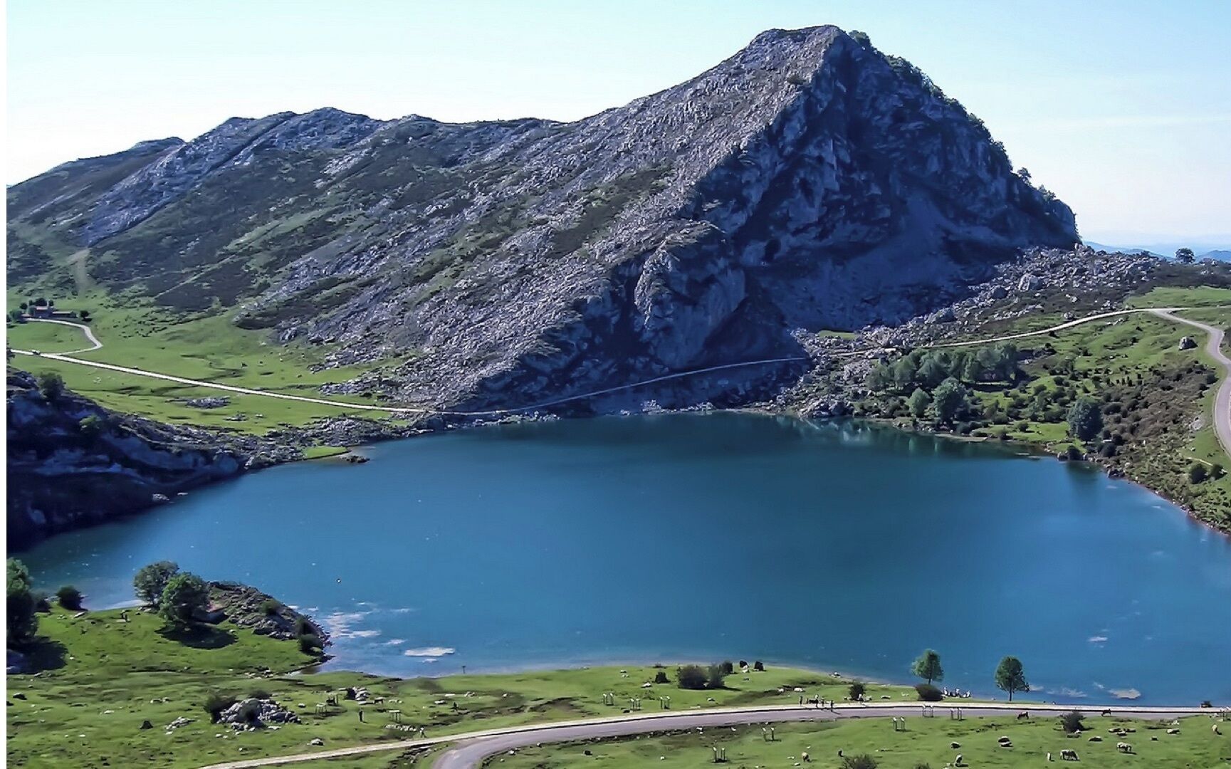 A mountainous landscape with a lake, roads, and scattered greenery.
