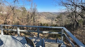 A wooden deck with metal railings overlooking a mountainous landscape.