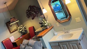 A modern kitchen with a wooden countertop, a sink, and a mirror above it. There is a red chair and a grey sofa with cushions.