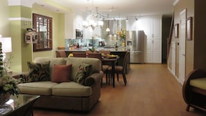 Una cocina moderna con armarios blancos, un refrigerador de acero inoxidable y un comedor con mesa y sillas.