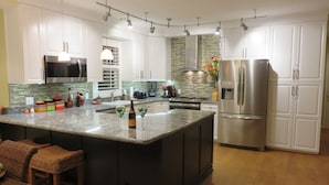 Una cocina moderna con armarios blancos, electrodomésticos de acero inoxidable y una isla grande con taburetes de bar.