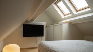 A bedroom with a skylight, a flat-screen TV, a bed with patterned bedding, and a round lamp. - MV 2 - L'Éveil de la Côte - House by the beach (Audresselles)