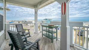 A covered outdoor area with a wooden deck, two chairs, a small table, and a thermometer. - ⚓Dock Holiday⚓ Oceanview, Close to Beach🌊 (Carolina Beach)