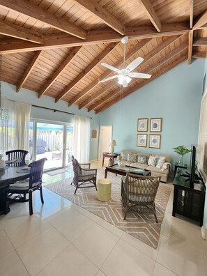 A spacious living area with a high ceiling, a ceiling fan, and a dining area with a table and chairs.