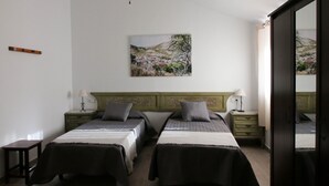 A bedroom with two beds, a ceiling fan, a painting on the wall, and a wooden floor. - CASA-MOLINO: Emerald pool. Ideal for families. Beautiful terrace. Views. (Jimera de Líbar)