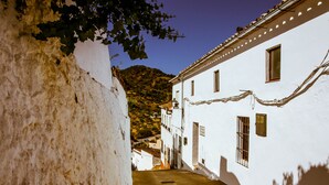 A narrow street with white buildings, a mountain in the background, and a clear sky. - CASA-MOLINO: Emerald pool. Ideal for families. Beautiful terrace. Views. (Jimera de Líbar)