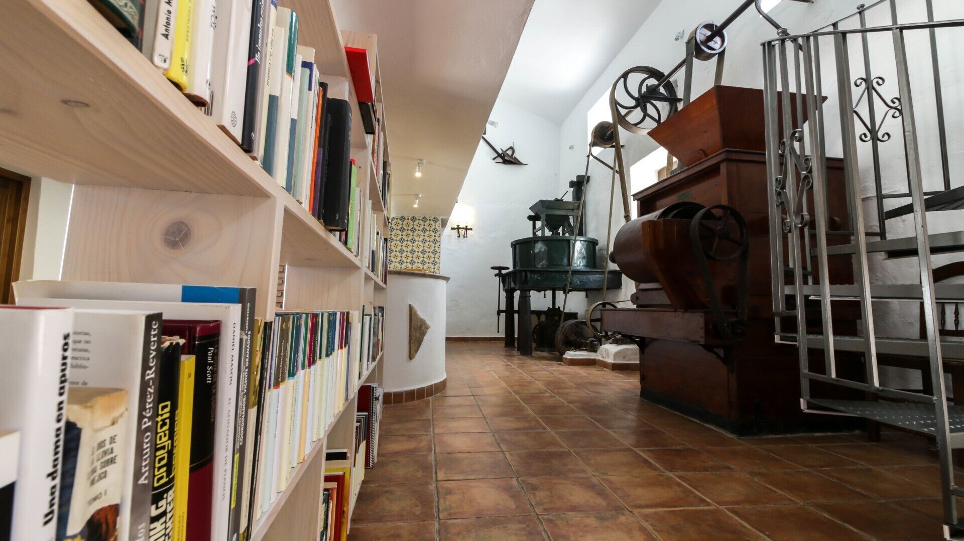 Een smalle gang met boekenkasten aan de ene kant en een grote, ouderwetse machine aan de andere kant.