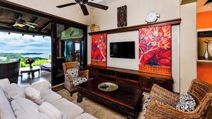 A living room with a sofa, two wicker chairs, a coffee table, a TV, and artwork on the walls. - Casa Pipilacha♛Ocean view Infinity Edge Pool with  in-law suite♛ (Tamarindo)