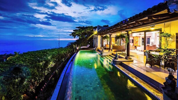 A poolside area with a view of the ocean, a covered patio, and a well-lit interior space. - Casa Pipilacha♛Ocean view Infinity Edge Pool with  in-law suite♛ (Tamarindo)