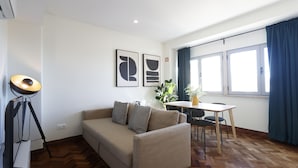 A modern living room with a sofa, a dining table, and a lamp.