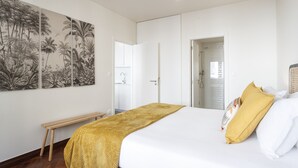 Ein Schlafzimmer mit einem Bett, einer Sitzbank, einer Tür und einer Wand mit einem tropischen Wandbild.
