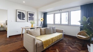 Ein modernes Wohnzimmer mit einer Couch, einem Esstisch und einem großen Fenster mit Vorhängen.