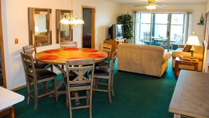 Un comedor con una mesa redonda y sillas, un sofá y un televisor al fondo.