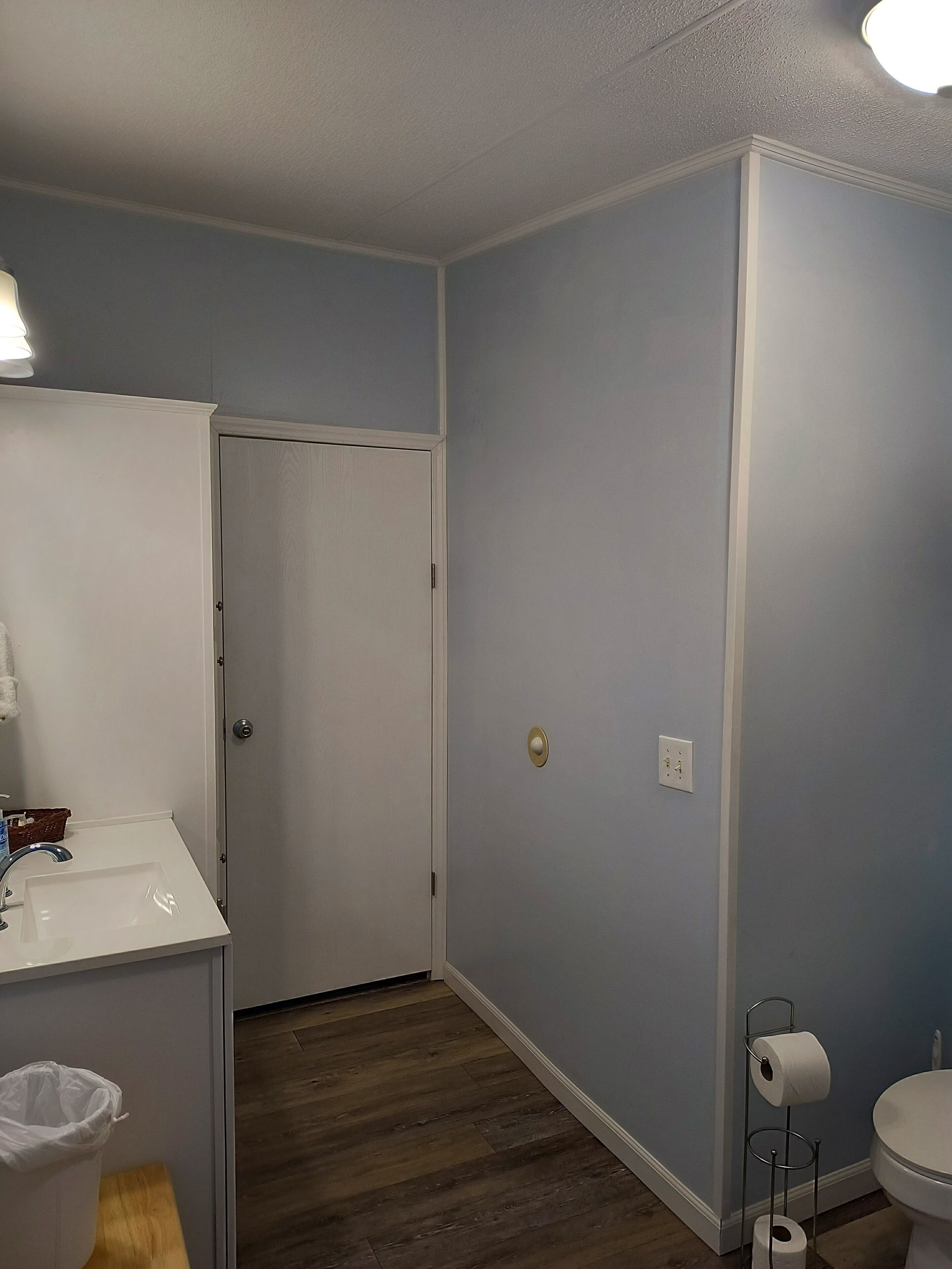 Ein Badezimmer mit einem weißen Waschbecken, einer Toilette und einer Tür zu einem anderen Raum.