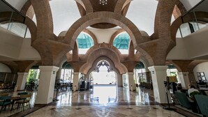 Eine großzügige Lobby mit hohen Ziegelbögen, einem polierten Boden und Tageslicht durch große Fenster.