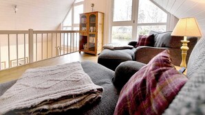 Ein gemütliches Schlafzimmer im Loft-Stil mit hohen Decken, einer Holzbücherwand, einer Couch und einer Lampe.