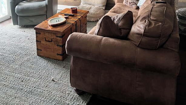Una sala de estar con una pared de madera, un ventilador de techo, un sofá, una silla y una mesa de centro.