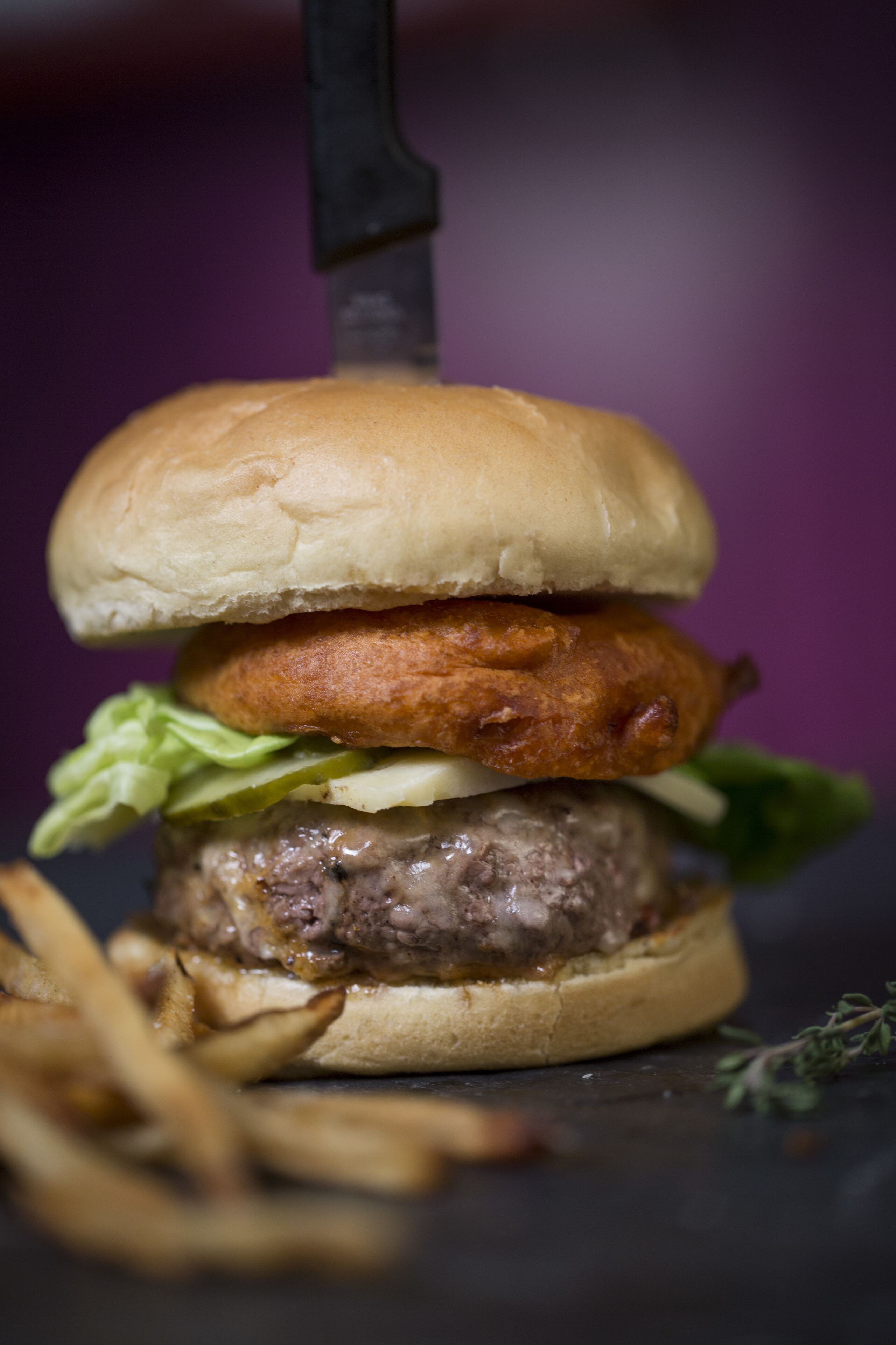 A burger with a bun, lettuce, and a beef patty, accompanied by fries.