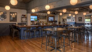 A bar area with stools, a counter, and a television screen.