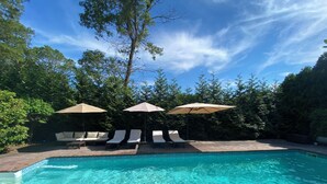 Une piscine d’un bleu éclatant, avec des chaises longues et des parasols.