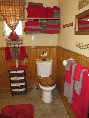 A bathroom with a toilet, a sink, and a mirror. There are towels and toiletries on shelves. - LA CASITA: Charm/Privacy, Stunning Patio, pet friendly (Bisbee)