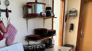 A kitchen with a stove, pots, and a coffee maker on a shelf. - LA CASITA: Charm/Privacy, Stunning Patio, pet friendly (Bisbee)