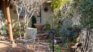A patio with a chair, a bird bath, a potted plant, and a decorative star on the wall. - LA CASITA: Charm/Privacy, Stunning Patio, pet friendly (Bisbee)