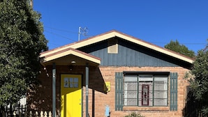 A two-story house with a yellow front door, a small porch, and a brick exterior. - LA CASITA: Charm/Privacy, Stunning Patio, pet friendly (Bisbee)