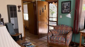 A living room with a patterned sofa, a coffee table, a ceiling fan, and a large window with curtains. - LA CASITA: Charm/Privacy, Stunning Patio, pet friendly (Bisbee)