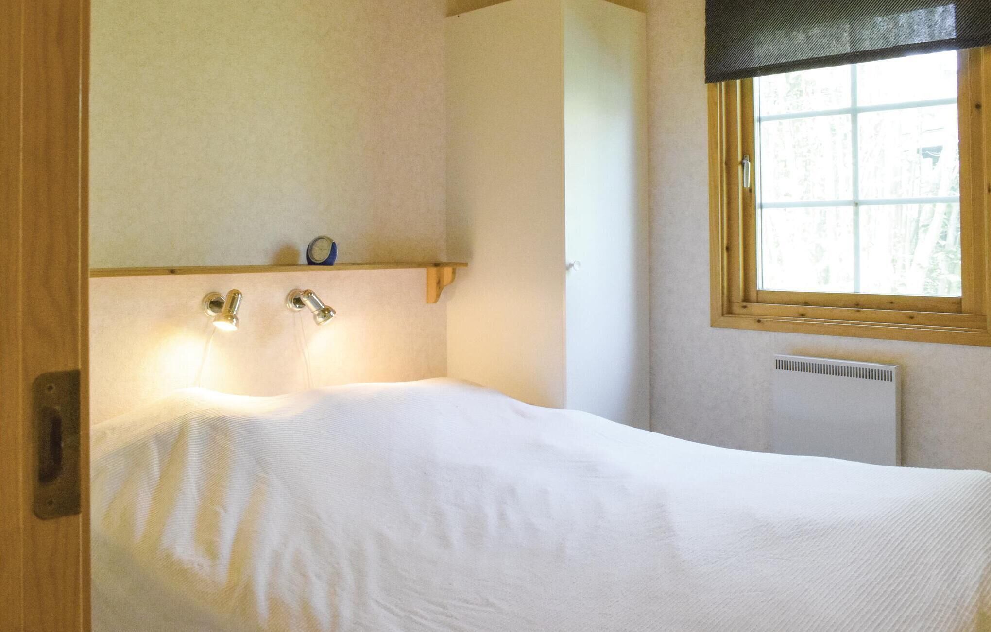 Une chambre à coucher avec un lit, une fenêtre donnant sur un beau paysage, un radiateur et une étagère avec une horloge.