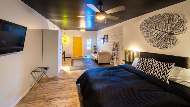 A modern bedroom with a bed, a ceiling fan, a flat-screen TV, and a decorative wall piece. - Downtown Cozy Condo -Walk to Best Diners, Breweries, NAU, Historic Flagstaff! (Flagstaff)