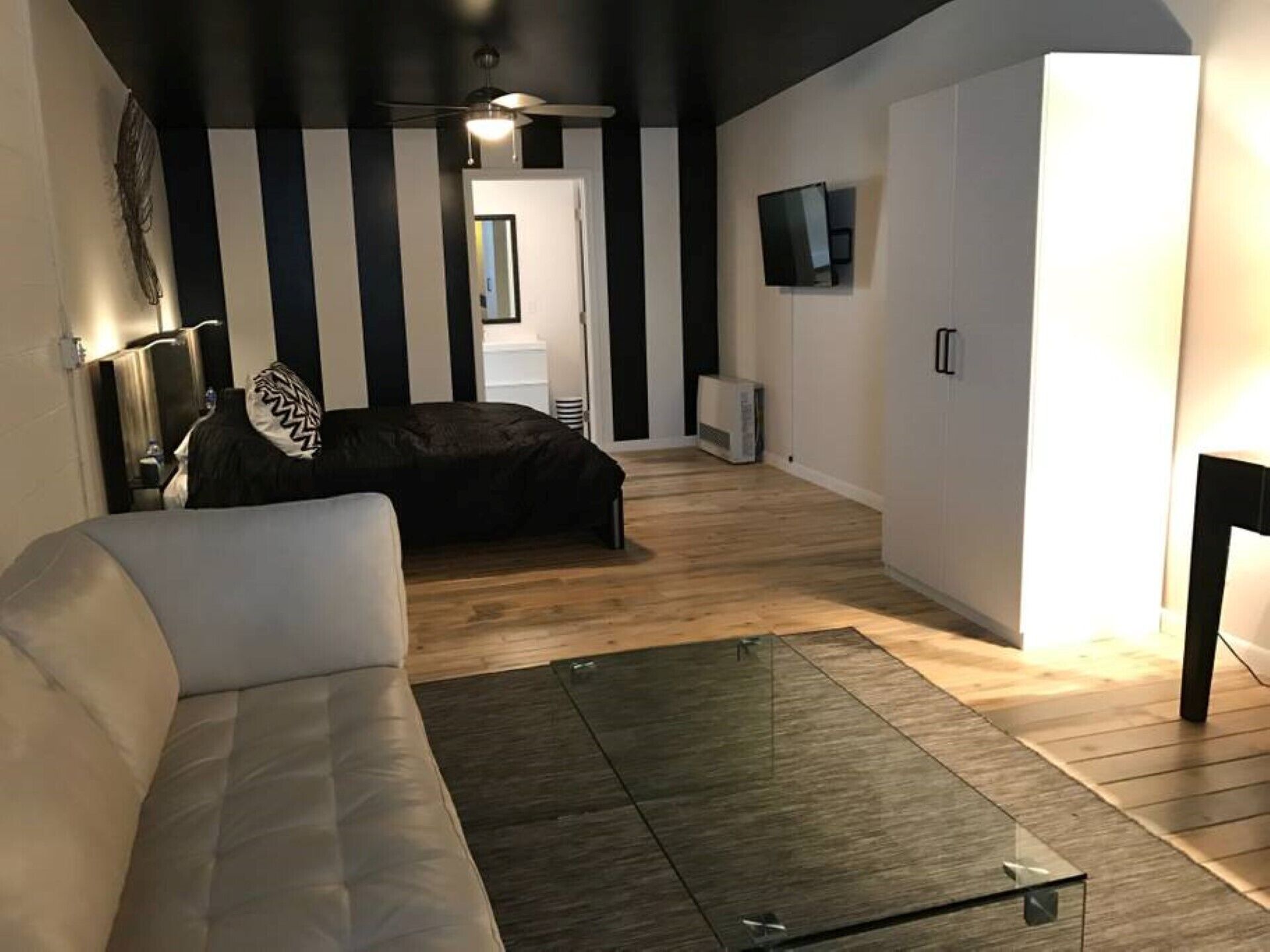 Ein modernes Wohnzimmer mit einer schwarz-weißen Streifenwand, einem Glastisch und einem Sofa.