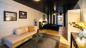A modern living room with a sofa, coffee table, and a bed in the background. - Downtown Cozy Condo -Walk to Best Diners, Breweries, NAU, Historic Flagstaff! (Flagstaff)