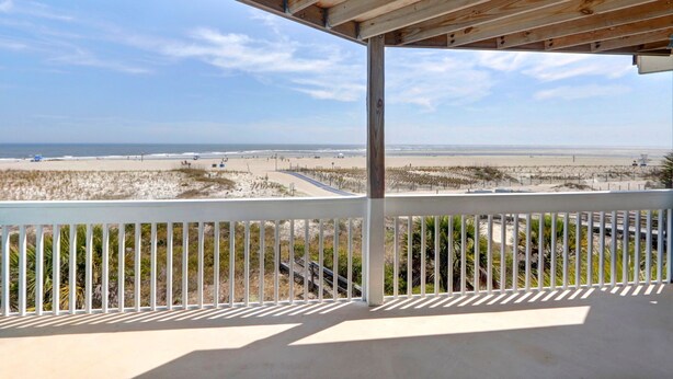 A balcony with a view of a beach and ocean.