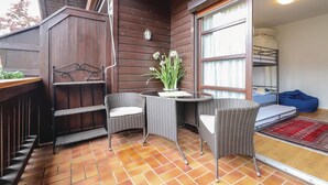 A cozy outdoor seating area with wicker chairs and a table, a small potted plant, and a view into a bedroom with bunk beds. - Beautiful home in Mondsee with house a mountain view (Mondsee)