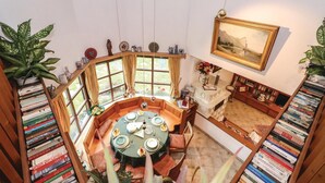 A dining area with a round table set for four, surrounded by bookshelves filled with books. - Beautiful home in Mondsee with house a mountain view (Mondsee)