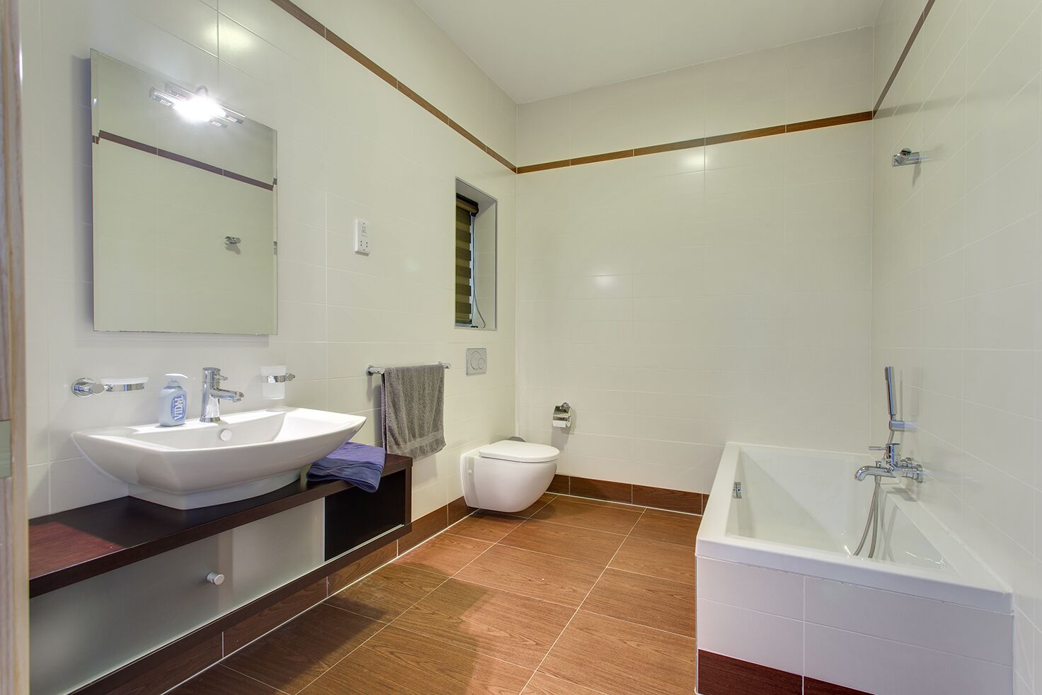 A modern bathroom with a large white sink, a toilet, and a bathtub.