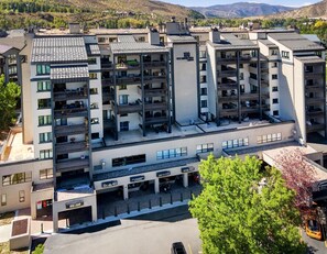 Un hotel de varios pisos con un estacionamiento al frente, balcones en cada nivel y vistas del paisaje circundante.
